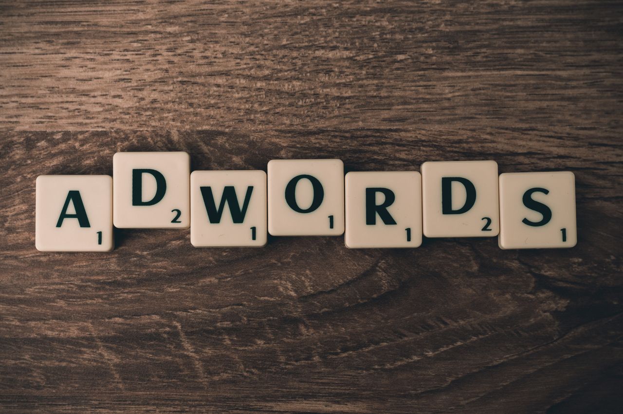about-us Scrabble tiles spelling AdWords on a wooden surface, symbolizing digital marketing concepts.